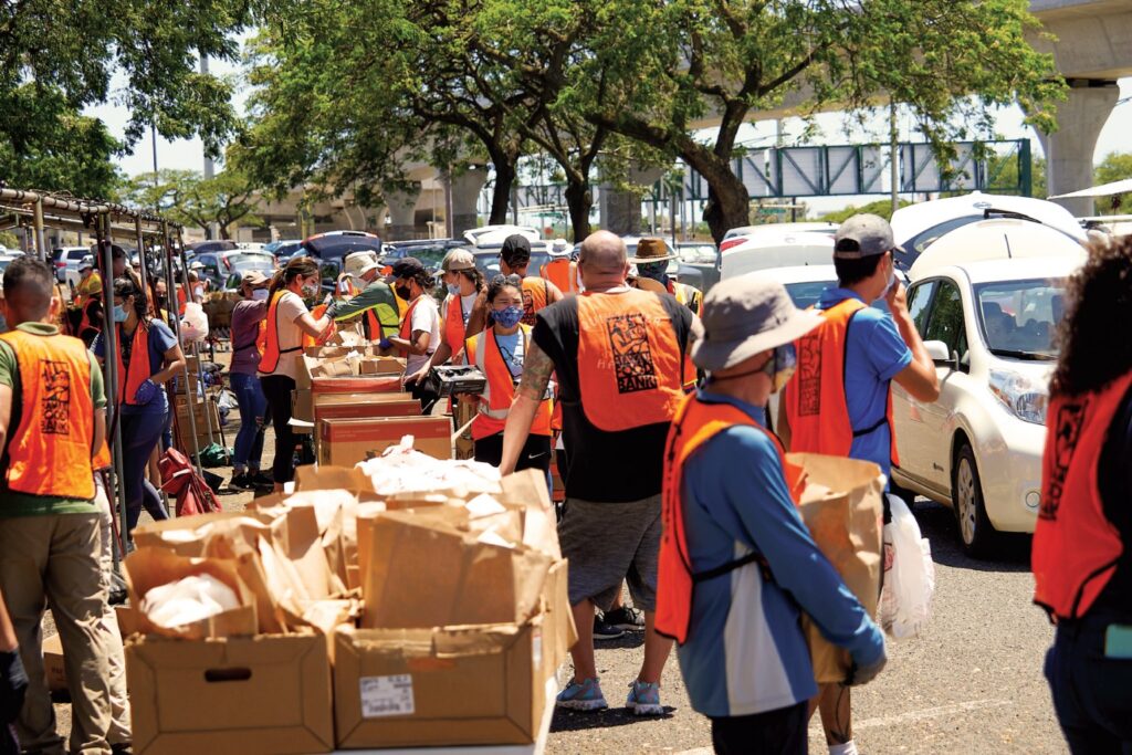 A large goup of Hawaii Food Bank volunteers distributing food to the community.