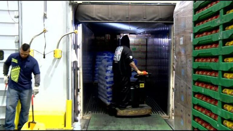 Coworkers unloading shipping crate of food.