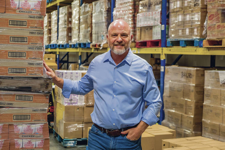 Chad Buck standing in front of a palette of food on the warehouse floor.